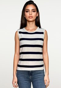 Mouwloos gestreept topje met marineblauwe en witte horizontale strepen, ronde halslijn, geribde textuur, gecombineerd met lichtblauwe jeans.