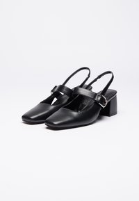 Sorte læderslingback-sko med firkantet tå, kraftig hæl og en bred rem foran, med sølvfarvet hardware.