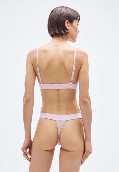 Rózsaszín fehérnemű szett puha, sima anyagból. A melltartó vékony, állítható pántokkal rendelkezik, a tanga pedig minimalista kialakítású, széles derékpánttal.