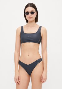 Sivi bikini set koji sadrži top s kvadratnim dekolteom i bočnim akcentima, te donji dio s niskim strukom i u obliku slova V. Glatki, rastezljivi materijal.
