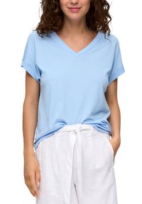 Lichtblauw V-hals T-shirt van zachte stof, met omgeslagen korte mouwen en een ontspannen pasvorm, gecombineerd met witte linnen broek.