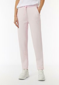Helle rosa Sweatpants mit einem elastischen Bund, Zugband, seitlichen Taschen und gesticktem Logodesign. Weicher Stoff und schmal zulaufendes Design.
