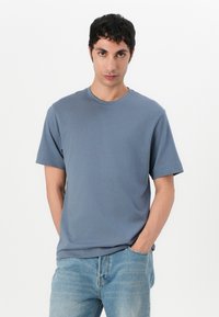 Blå bomulls t-skjorte med rund hals og korte ermer, sammen med lyseblå denim. Enkel design, glatt tekstur, og ingen synlige mønstre.