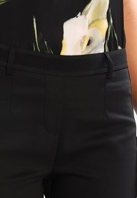 Sorte tætsiddende bukser med en tekstureret linning og en glat finish. Designet inkluderer forlommer og skræddersyede syninger.