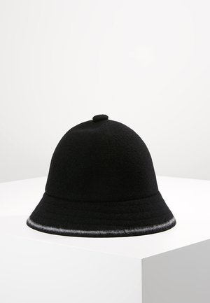 Cappello cloche in feltro nero con corona arrotondata, piccolo bottone in tessuto in cima e un orlo leggermente più chiaro, esposto su una superficie bianca.