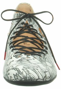 Scarpa stringata con un motivo astratto bianco e nero, materiale in suede, punta rotonda, lacci neri e un accento rosso sul tallone.