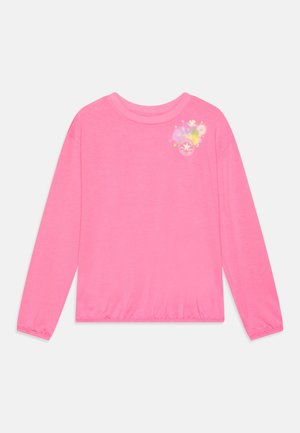 Chemise à manches longues rose vif avec poignets et ourlet élastiques, ornée d'un petit motif floral et du logo Converse sur la partie supérieure gauche de la poitrine.