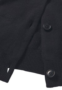 Schwarze gestrickte Strickjacke mit geripptem Muster, fünf großen schwarzen Knöpfen und einem seitlichen Schlitz für zusätzliche Flexibilität.