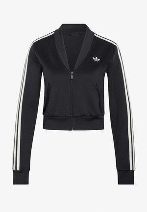 Giacca sportiva nera con zip e tre strisce bianche sulle maniche, con un piccolo logo trefoil bianco di Adidas sul petto sinistro.
