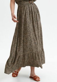 Maxikjol i mönstrat tyg med virvlande linjer i beige och svart; åtsittande midja med elastik och volangdetalj i nederkant.