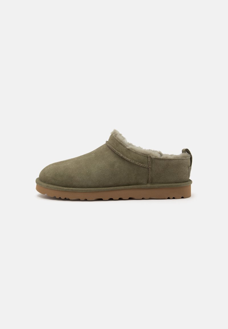 Chausson à enfiler avec extérieur en daim olive, doublure intérieure douce et claire, et semelle en caoutchouc marron clair texturée.