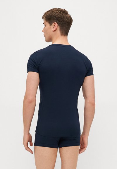 T-shirt ajustado azul marinho, feito de um tecido suave, com mangas curtas e gola redonda, combinado com calções justos a condizer.