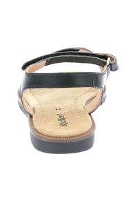 Sandal in pelle nera con suola piatta, plantare beige testurizzato e cinturino regolabile. Design semplice con accenti minimalisti.