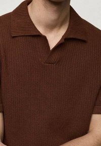 Camisa polo de punto acanalado marrón con cuello y mangas cortas. Presenta una pequeña tapeta y un tejido texturizado.