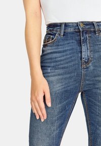 Högmidjade blå denimjeans med en blekt tvätt, framfickor och dragkedja med en enkel knäppning.