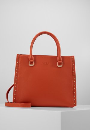Sac à main orange texturé avec deux poignées, clous dorés sur les côtés et bandoulière amovible sur surface blanche.