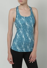 Top in tessuto leggero e elasticizzato, di colore turchese con motivo triangolare. Presenta un collo rotondo e uno stile racerback.
