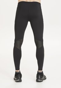 Mustat urheilulegginsit, joissa on sileä ja joustava rakenne, ja joissa on verkkopaneelit alhaalla jaloissa sekä kaksi sivutaskua.