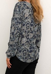 Blusa navy con motivo paisley in crema e azzurro chiaro, presenta maniche lunghe e arricciate e un collo rotondo, realizzata in tessuto leggero.