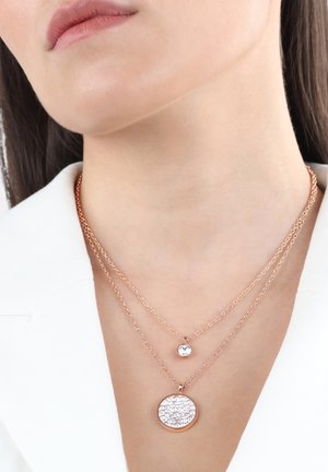 Collane sovrapposte in oro rosa con un piccolo pendente rotondo e un pendente circolare più grande e scintillante, caratterizzato da una superficie testurizzata e glitterata.