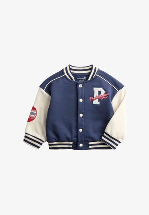 Veste universitaire bleu marine avec manches crème, col côtelé rayé, fermeture à boutons, broderie « P » et texte « Paddington ».