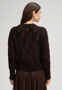 Ciemnobrązowy sweter z dzianiny z teksturowanym wzorem, ściągaczami przy mankietach i dolnej krawędzi oraz małym logo na tylnej części dekoltu.