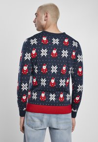 Pulover tricotat de culoare bleumarin, cu motive de Moș Crăciun și fulgi de zăpadă, având tiv și manșete roșii, confecționat dintr-un material textil moale.