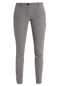 Aansluitende broek met een geometrisch zwart-wit patroon, met een strakke vormgeving, een gladde textuur en zwarte accentueringen aan de zijkanten.