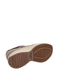 Semelle de sneaker marron et beige avec une texture en caoutchouc antidérapant, présentant un logo de marque discret et des accents de couleur contrastés.