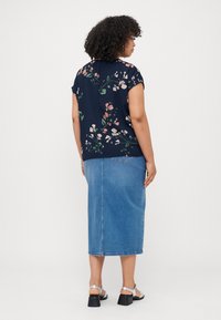 Navy floral top with short sleeves paired with a denim midi skirt. Silver sandals with a block heel complete the outfit.