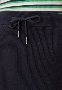 Marine gebreide sweatpants hebben een textuur met ribbelontwerp, een elastische tailleband met een stoffen strik en zilveren metalen uiteinden op de koorden.