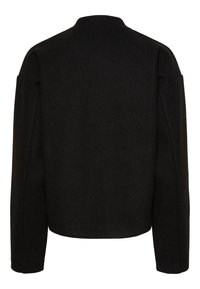 Veste en laine noire avec un col montant, des épaules tombantes et une coupe droite. Présente des coutures minimales et ne comporte pas de fermetures visibles.
