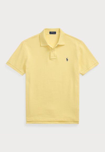 Polo shirt galben deschis dintr-un material texturat, cu mâneci scurte, placket cu trei nasturi și un mic logo bleumarin pe partea stângă a pieptului.