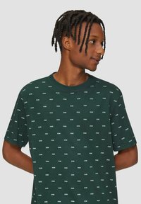Donkergroene t-shirt met korte mouwen met een herhaald patroon van een wit logo. Ronde hals, gemaakt van katoen, casual pasvorm.