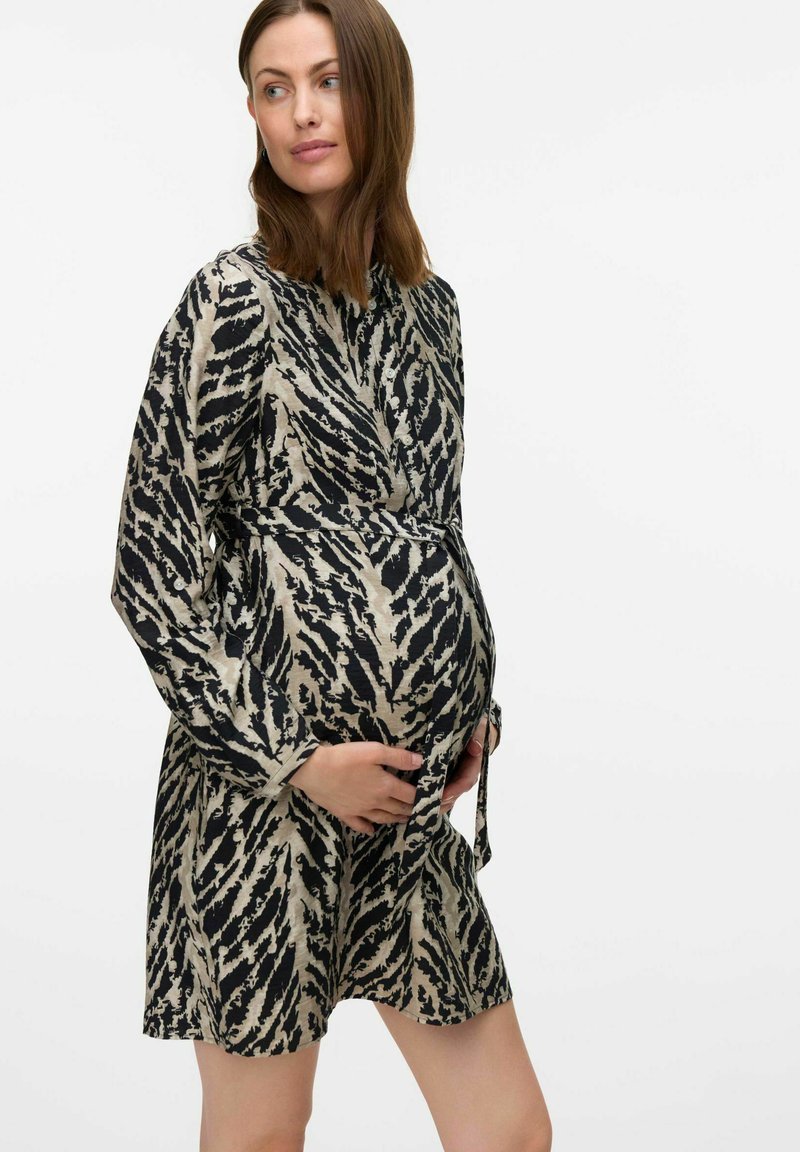 Robe de maternité en tissu imprimé, présentant un motif abstrait noir et beige, des manches longues, une taille ceinturée et une coupe décontractée.