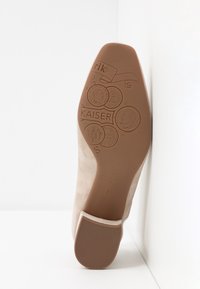 Semelle de chaussure en daim beige avec des pièces en relief, marquage "KAISER" et "Peter Kaiser Allemagne depuis 1838" dans un coin blanc.
