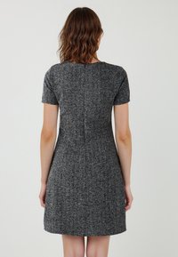 Abito a maniche corte, svasato, in tweed nero e grigio, con un collo rotondo e una texture liscia, caratterizzato da un dettaglio con cucitura sul retro.