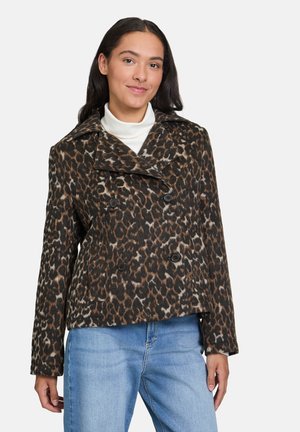 Veste double boutonnage en imprimé léopard en tissu texturé, avec col à revers et boutons noirs, assortie à un jean bleu.