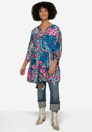 Tunique multicolore avec des imprimés animaliers bleus, roses et noirs ; coupe ample, col en V, manches trois-quarts, détail de volants superposés au bas.