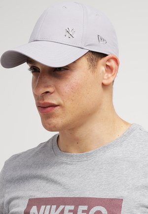 Lys grå baseballkasket med broderet NY-logo, struktureret design og krum skygge. Båret med en grå t-shirt med logo.