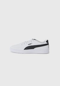 Baskets blanches en matériau synthétique avec un accent noir sur le côté, présentant une semelle plate et un design minimaliste.