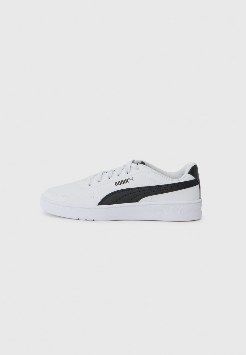 Baskets blanches en matériau synthétique avec un accent noir sur le côté, présentant une semelle plate et un design minimaliste.