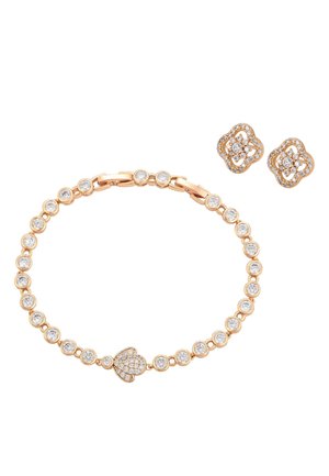 Gouden armband met ronde heldere stenen en een hartvormige hanger, gecombineerd met gouden oorstekers in bloemvorm, bezet met kleine heldere stenen.