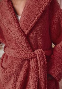 Fleece bathrobe in a textured coral color with a shawl collar, tie belt, and two front pockets. Soft, warm material.
