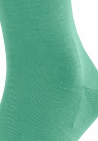 Grüne Baumwollsocke mit glatter Textur, die ein geripptes Design aufweist und an den Zehen- und Fersenbereichen verstärkt ist für mehr Haltbarkeit.