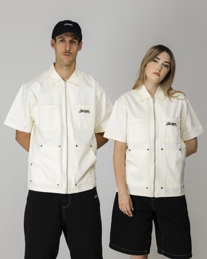 White denim zip-up jackets with large pockets, worn with black shorts. Features brand logo in black thread on the chest.