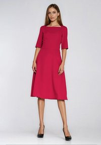 Midi sukienka w kolorze fuksji z kwadratowym dekoltem, krótkimi rękawami i dopasowaną talią. Wykonana z gładkiej tkaniny, z rozkloszowanym dołem i ukrytymi kieszeniami.