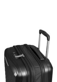 Maleta dura negra con superficie texturizada, cremalleras dobles, cerradura incorporada y asa plateada retráctil. Ruedas suaves no mostradas.