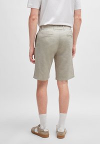 Shorts beige chiaro realizzati in un mix di lino. Presentano una vestibilità rilassata, frontale piatto e tasche posteriori. Indossati con calze bianche e sneakers beige.