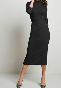 Black long-sleeve fitted top paired with a black pencil skirt, featuring a smooth texture and knee-length design. Snake print high heels.